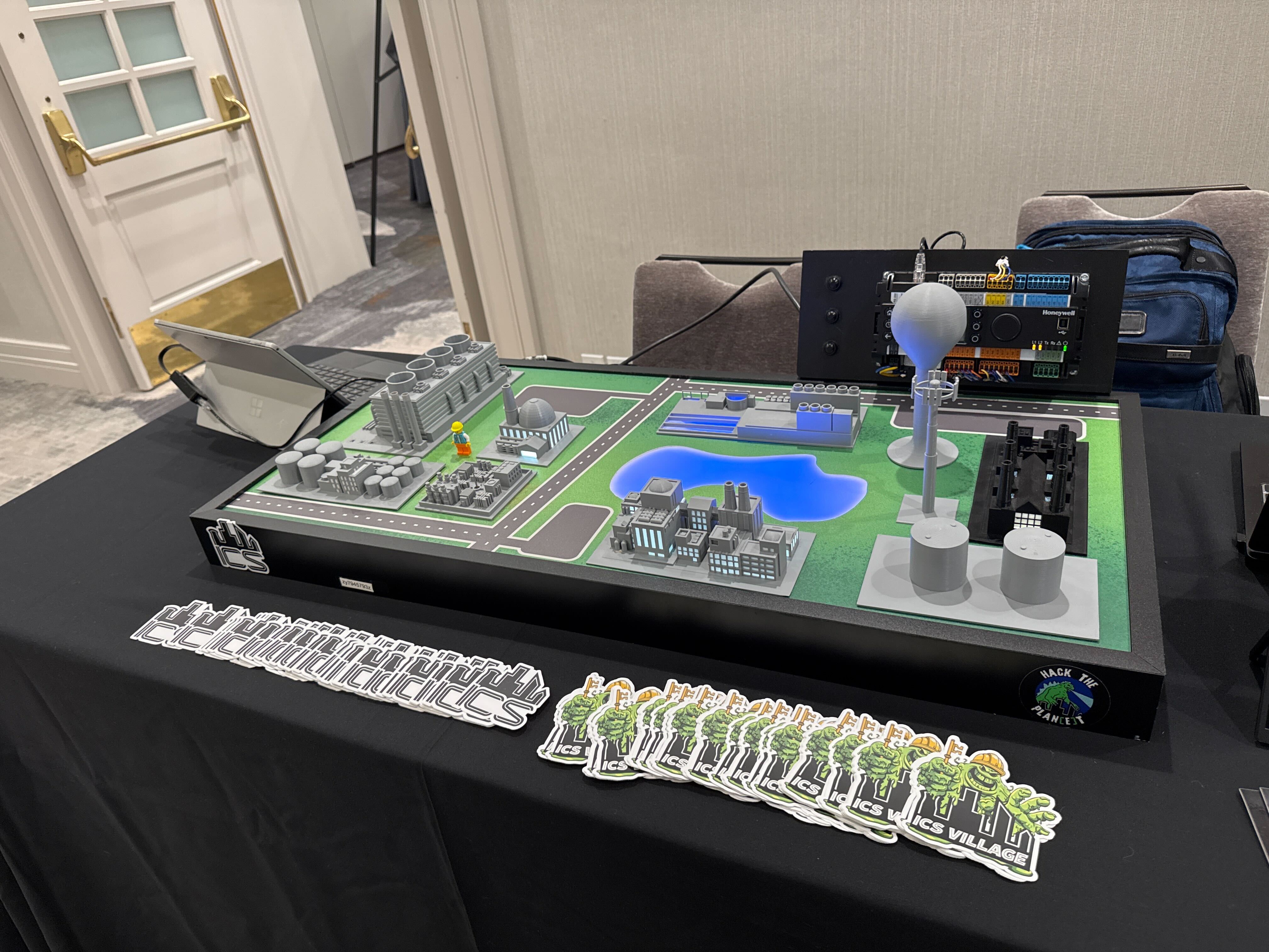 The ICS Village OT Trainer Kit — a working scale-model industrial site with real PLCs and HMI, deployed at BSides and DEF CON.
